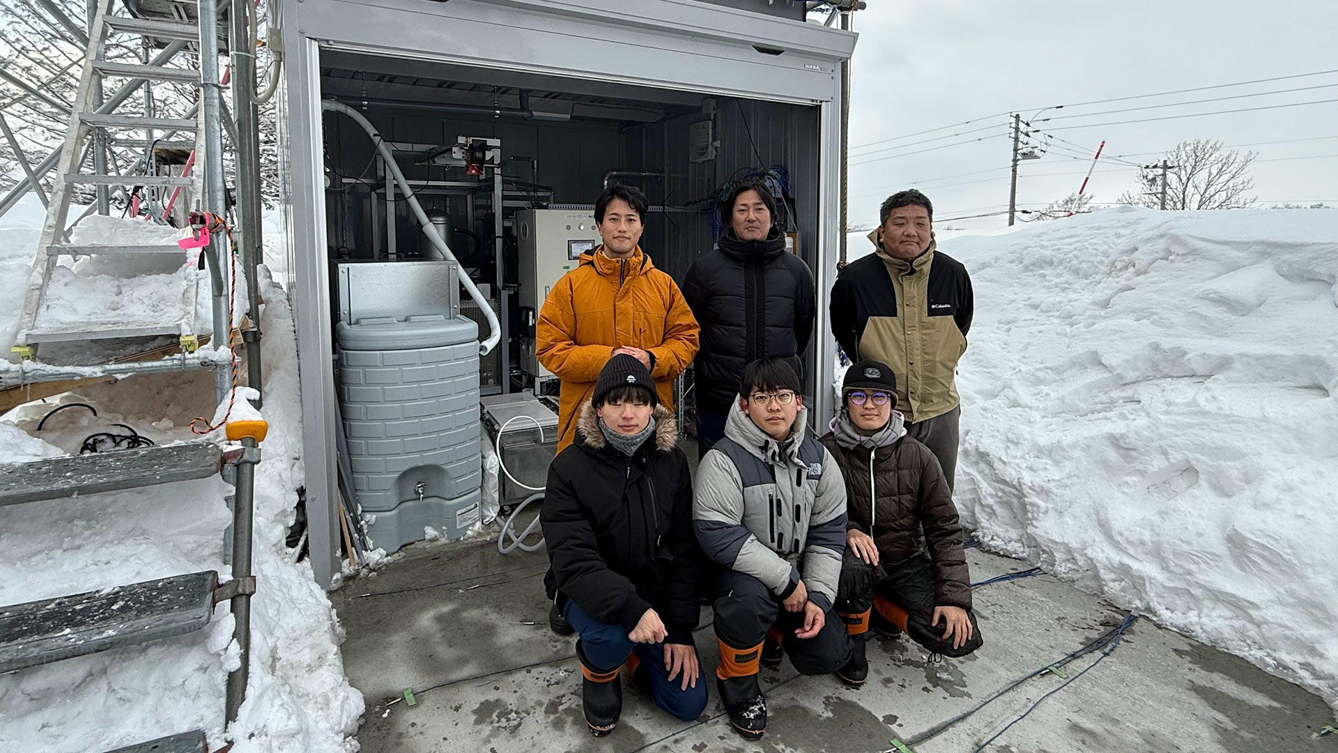 写真）雪発電設備の前で　電気通信大学 榎木光治准教授と研究室の学生ら